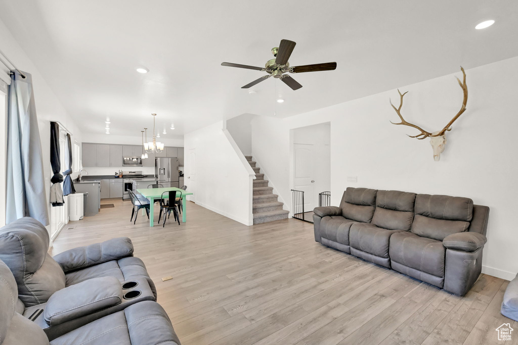 Living area featuring light wood finished floors, a ceiling fan, recessed lighting, baseboards, and stairs
