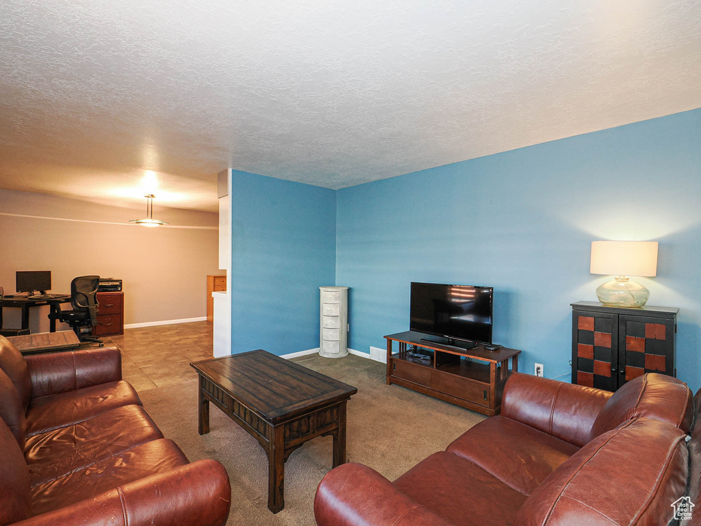Living room featuring an office area, carpet flooring, baseboards, and a textured ceiling