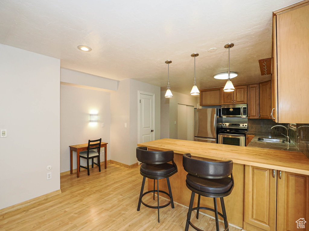 Kitchen with stainless steel appliances, butcher block counters, a sink, a peninsula, and recessed lighting