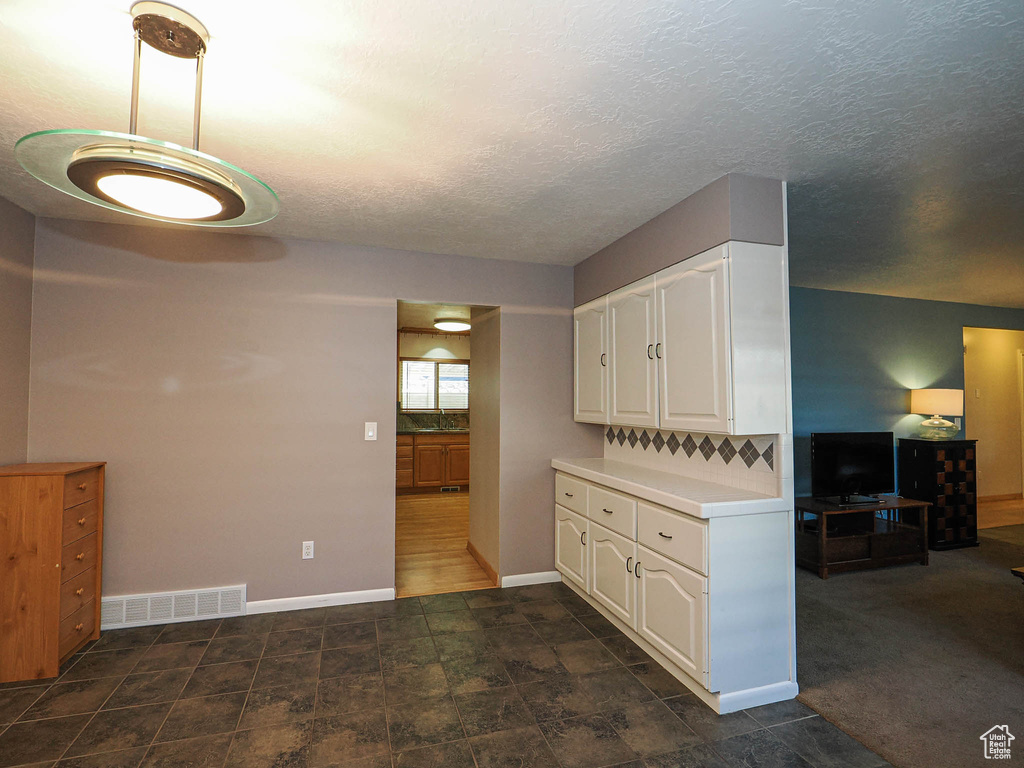 Kitchen featuring white cabinets, light countertops, baseboards, and a textured ceiling