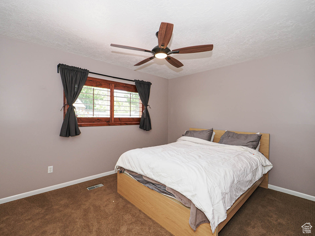 Bedroom featuring baseboards, a textured ceiling, carpet, and a ceiling fan