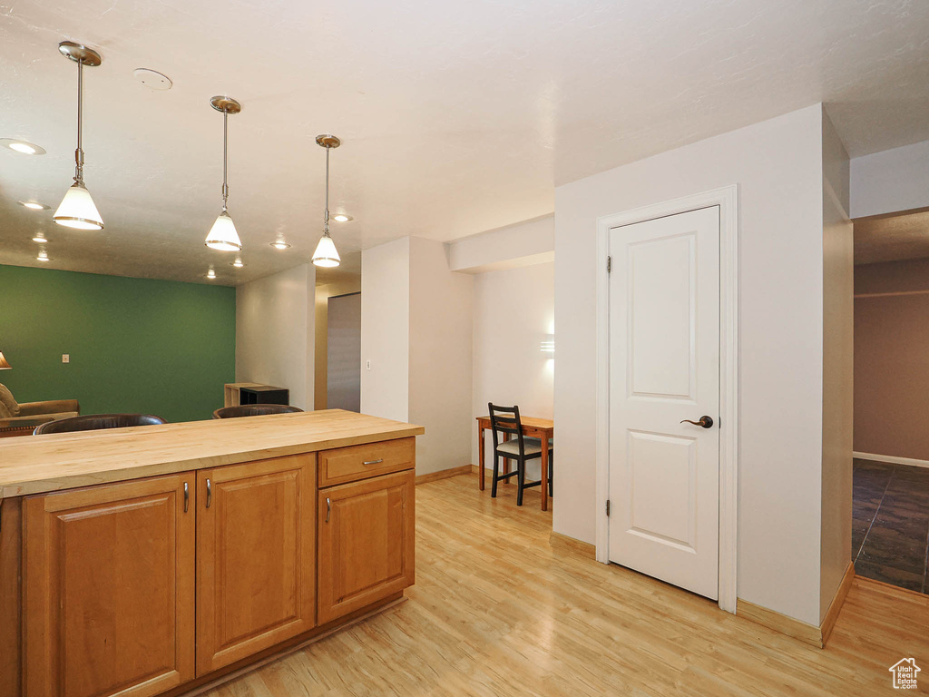 Kitchen featuring butcher block countertops, decorative light fixtures, light wood-style flooring, baseboards, and recessed lighting