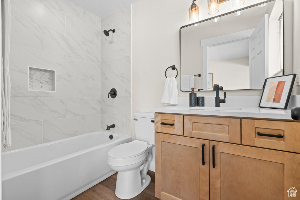Bathroom with toilet, vanity, bathtub / shower combination, and wood finished floors