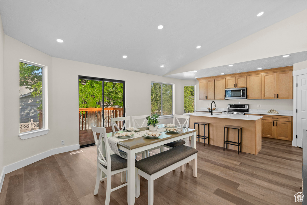 Dining space featuring wood finished floors, healthy amount of natural light, lofted ceiling, and recessed lighting