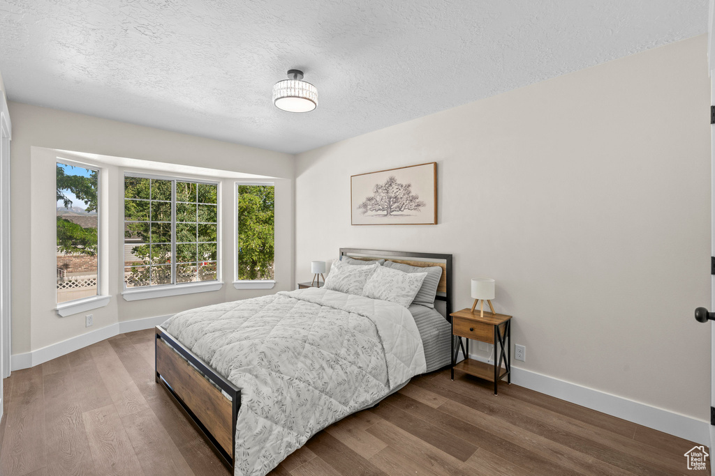 Bedroom with baseboards, wood finished floors, and a textured ceiling