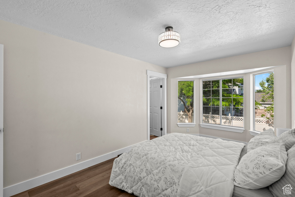 Bedroom with dark wood-style floors, baseboards, and a textured ceiling