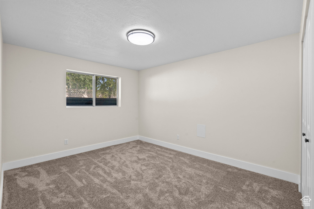 Carpeted empty room with baseboards and a textured ceiling