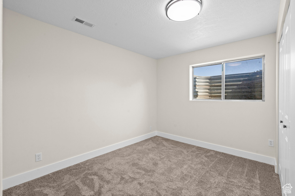 Spare room with carpet floors, baseboards, and a textured ceiling