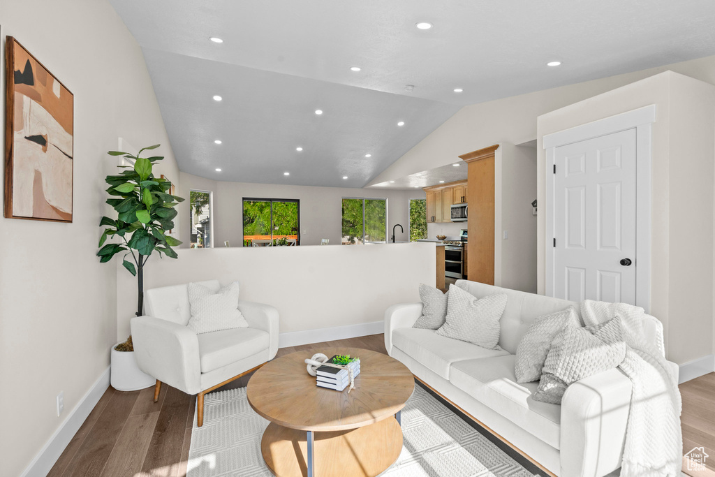 Living area featuring lofted ceiling, light wood-style floors, recessed lighting, and baseboards