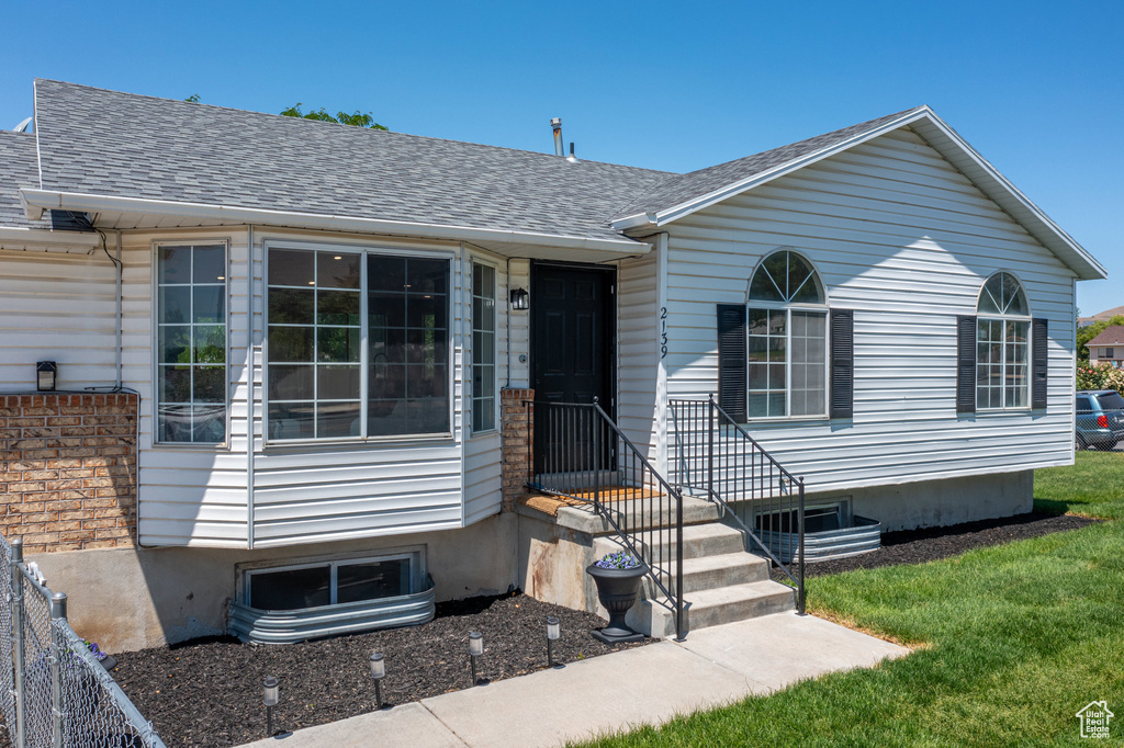 View of front facade featuring roof with shingles and a front yard