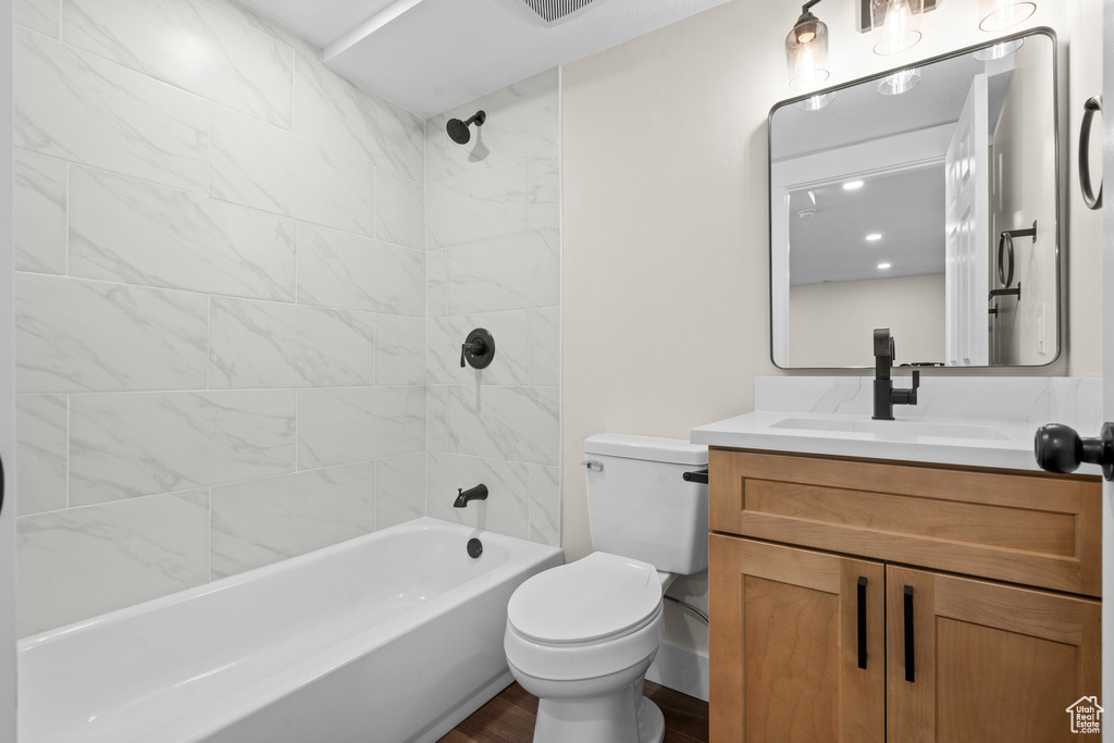 Full bath with toilet, vanity, wood finished floors, and washtub / shower combination