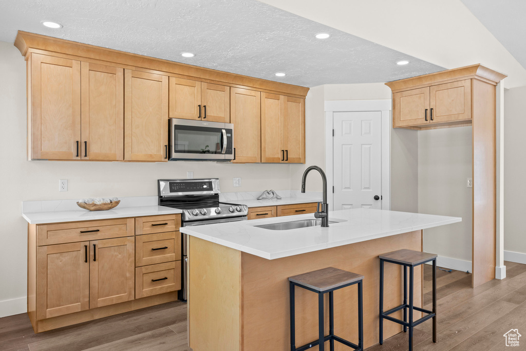 Kitchen featuring appliances with stainless steel finishes, a sink, light wood-style floors, baseboards, and recessed lighting