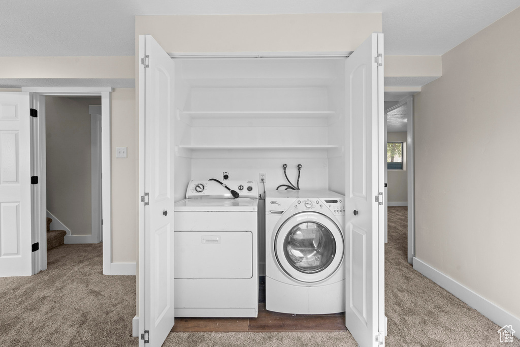 Washroom with washing machine and dryer, dark carpet, and baseboards