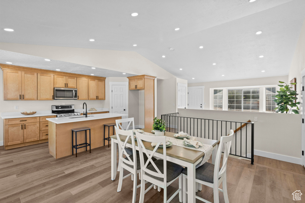 Dining room with vaulted ceiling, light wood-style floors, recessed lighting, and baseboards