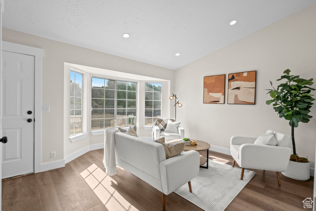 Living room with vaulted ceiling, light wood-style floors, baseboards, and recessed lighting