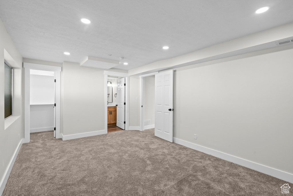 Unfurnished bedroom with carpet, recessed lighting, a spacious closet, baseboards, and ensuite bath