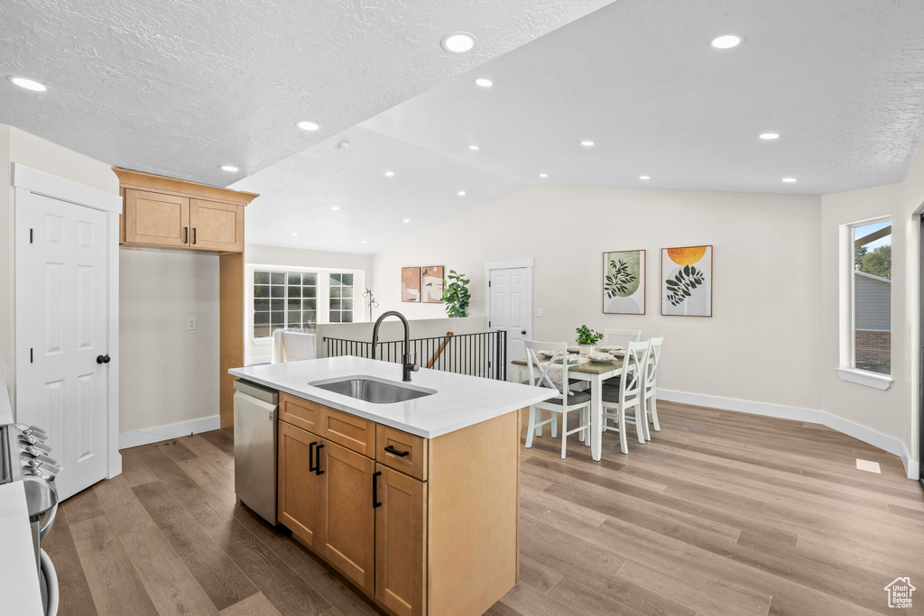 Kitchen with stainless steel appliances, a sink, light wood finished floors, baseboards, and recessed lighting