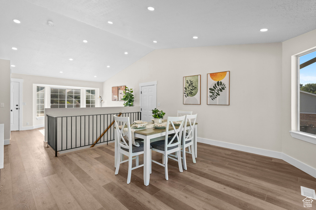 Dining space with lofted ceiling, wood finished floors, baseboards, and recessed lighting