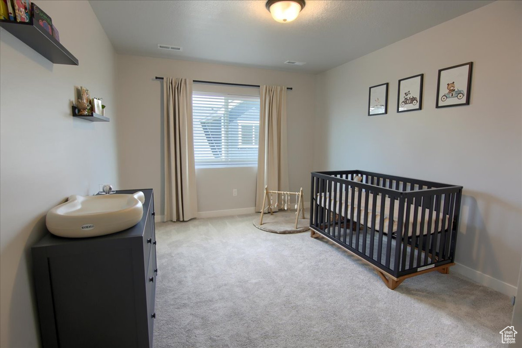 Carpeted bedroom featuring a nursery area and baseboards