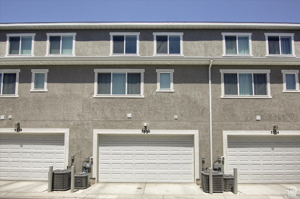 Rear view of property featuring stucco siding and central AC