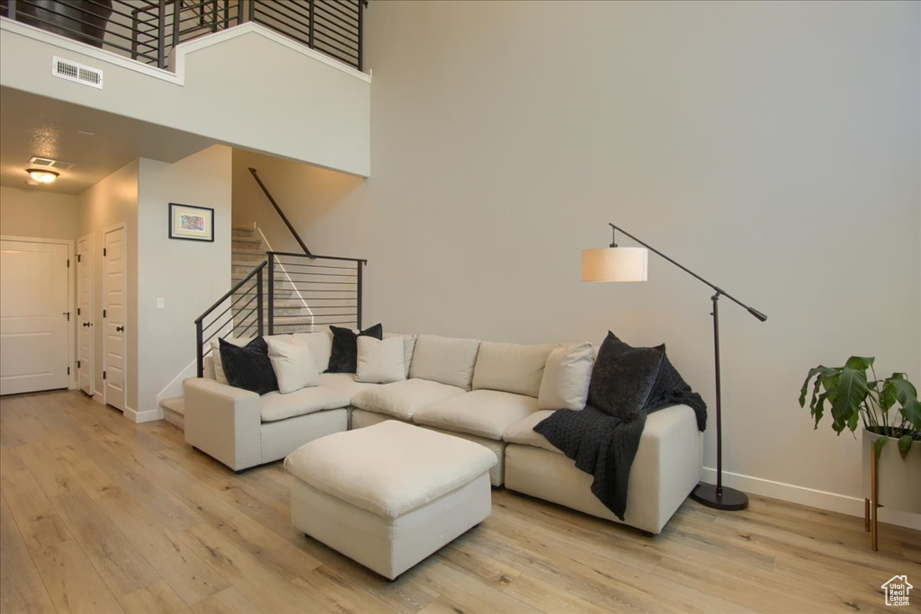 Living area with light wood-type flooring, stairs, baseboards, and a towering ceiling