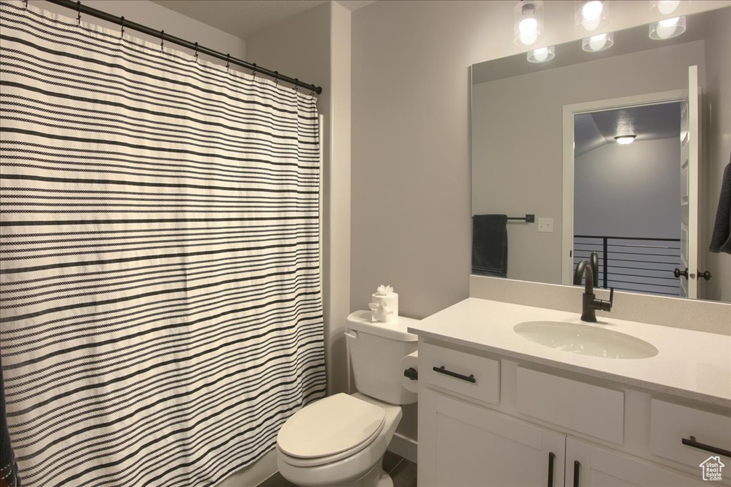 Bathroom with toilet, vanity, and a shower with curtain