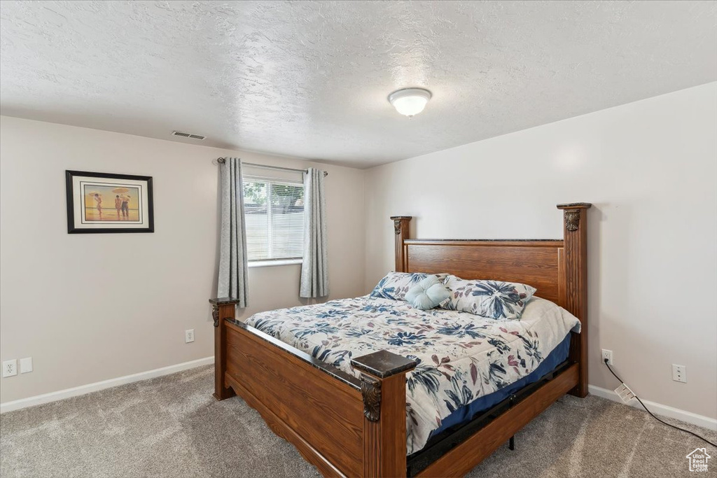Carpeted bedroom with a textured ceiling and baseboards