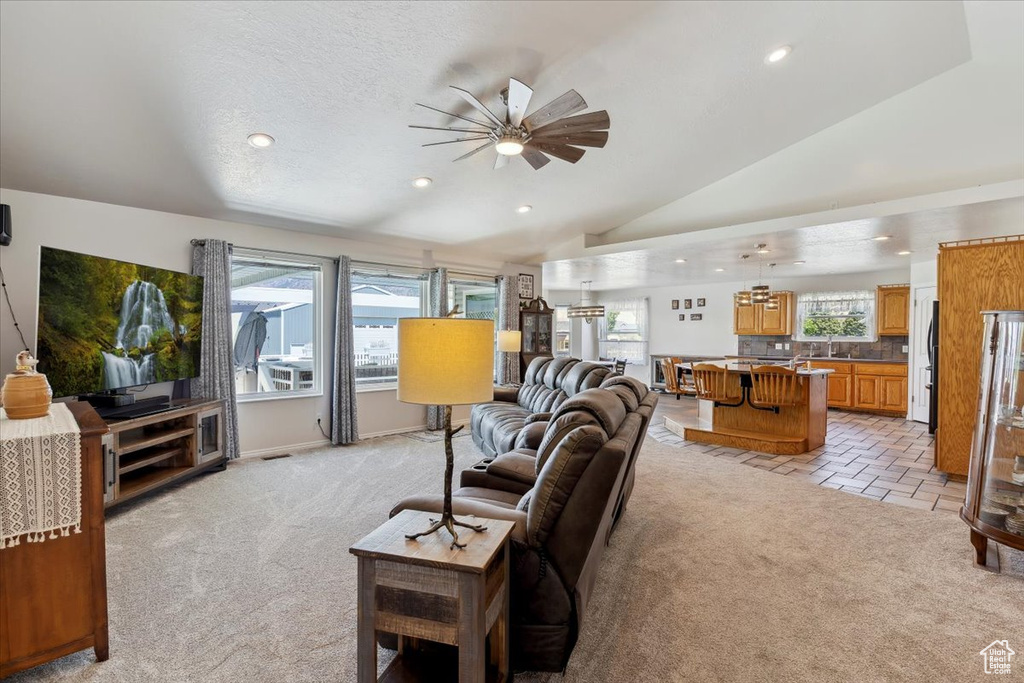 Living area featuring light colored carpet, a ceiling fan, recessed lighting, and vaulted ceiling