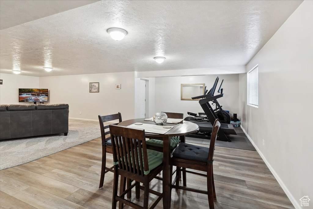 Dining space with wood finished floors, baseboards, and a textured ceiling