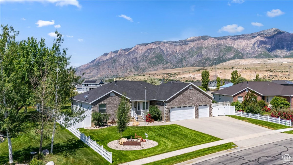 View of front of property with a garage, a mountain view, driveway, and stone siding