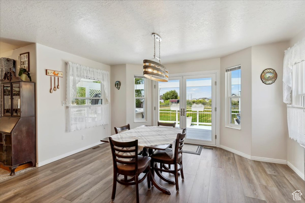 Dining area featuring wood finished floors, a textured ceiling, french doors, and baseboards