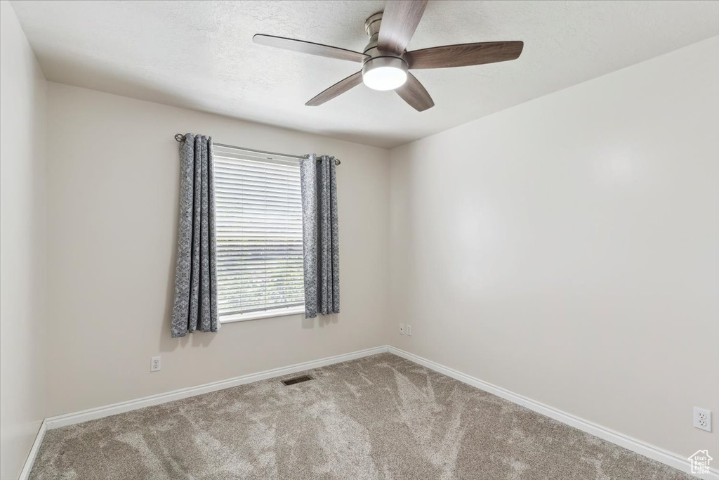 Empty room featuring baseboards, carpet floors, and ceiling fan