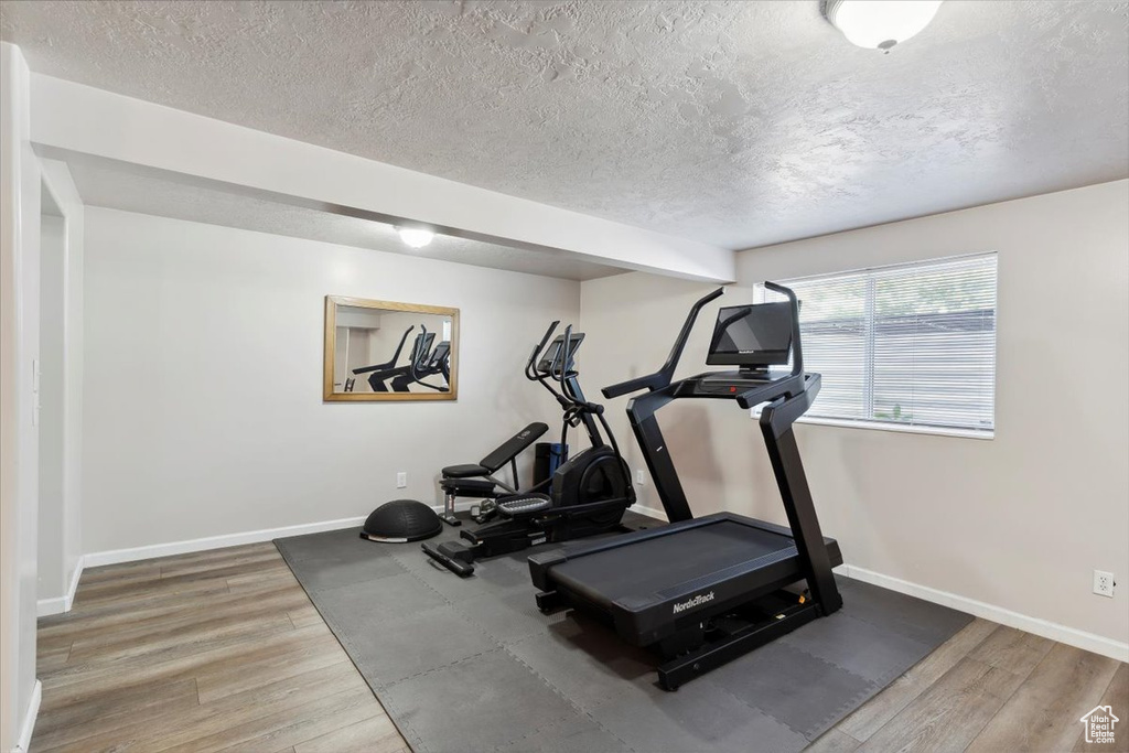 Workout area featuring a textured ceiling, wood finished floors, and baseboards