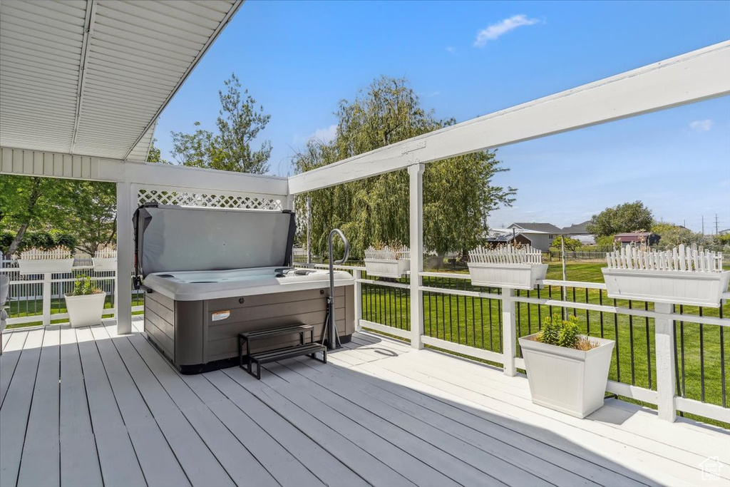 Deck featuring a hot tub and a lawn
