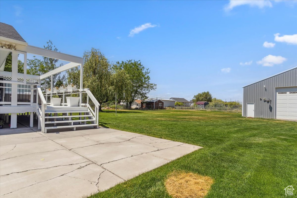 View of grassy yard with a wooden deck and a detached garage