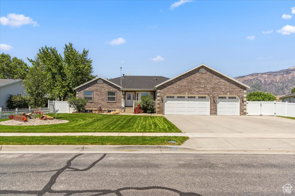 Ranch-style house with an attached garage, concrete driveway, brick siding, and a mountain view