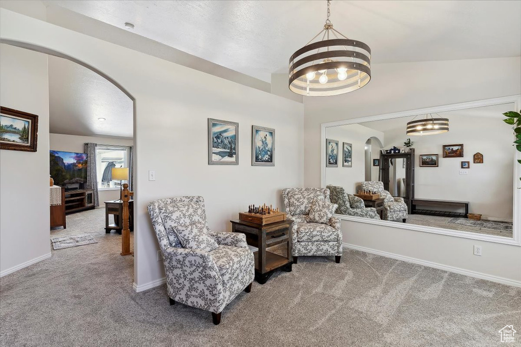 Sitting room featuring arched walkways, carpet, a chandelier, baseboards, and lofted ceiling
