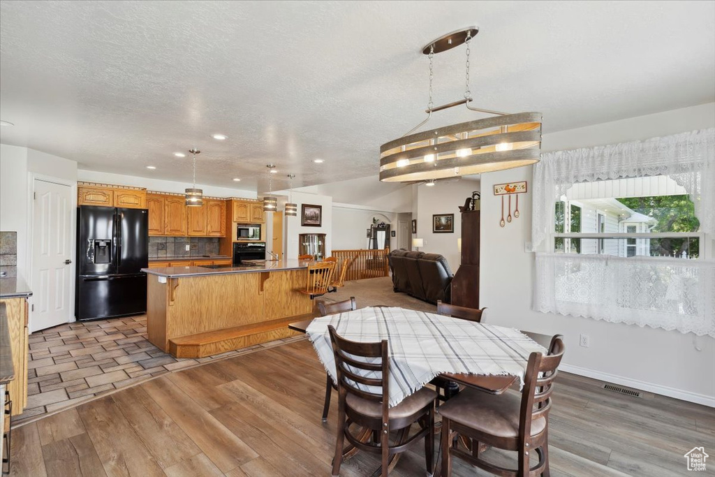 Dining area with light wood-style flooring, a textured ceiling, and recessed lighting