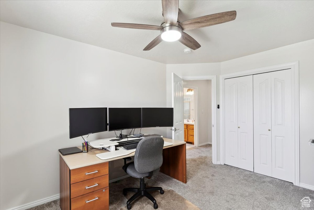 Office space with light carpet, a ceiling fan, and baseboards