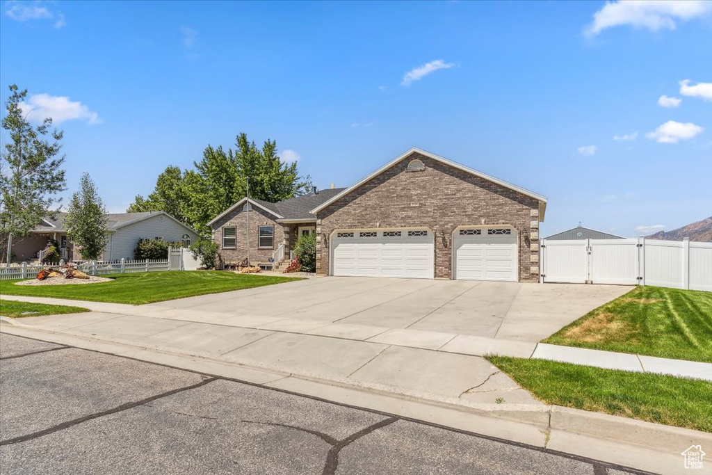 Single story home featuring a gate, driveway, a garage, and brick siding