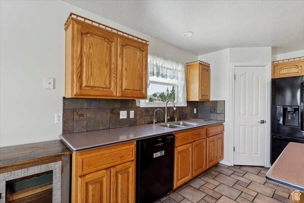 Kitchen with black appliances, a sink, wine cooler, decorative backsplash, and stone finish floors