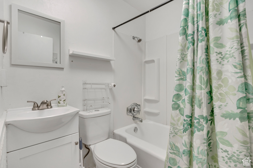 Bathroom with shower / bathtub combination with curtain, toilet, and vanity
