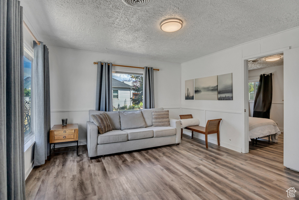 Living area with plenty of natural light, wood finished floors, and a textured ceiling