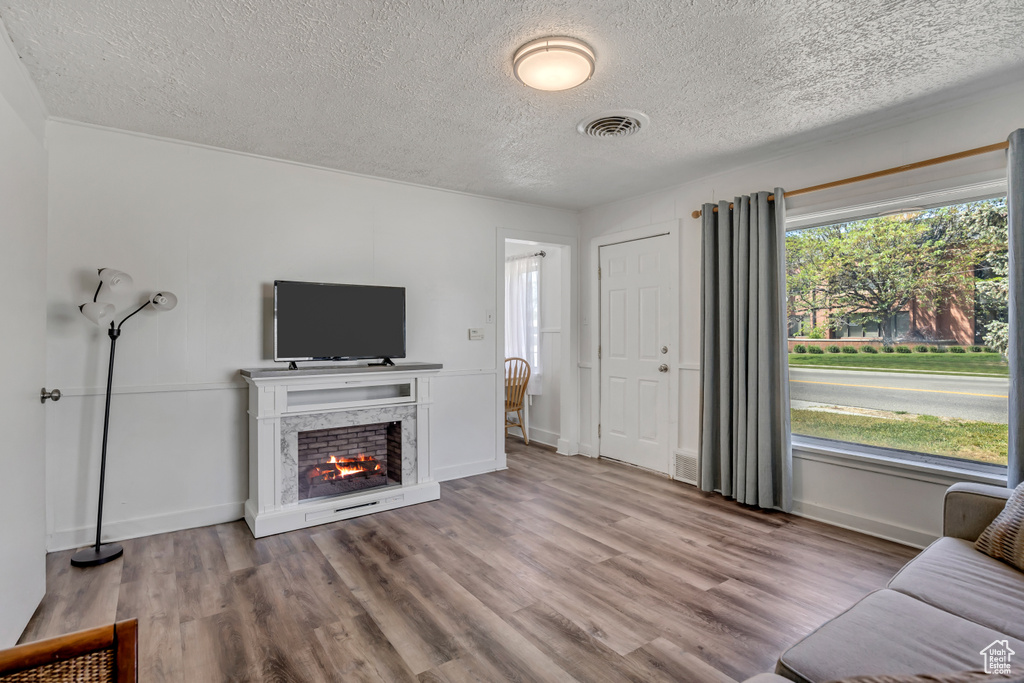 Living area with a textured ceiling, wood finished floors, a fireplace, and baseboards