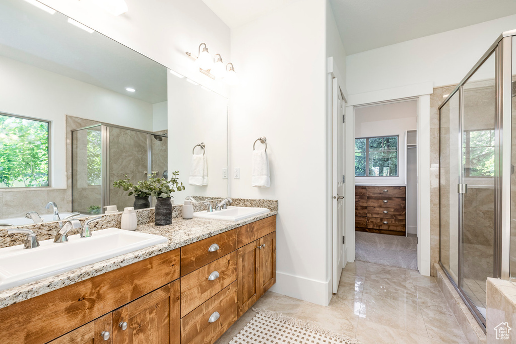 Full bathroom featuring double vanity, a stall shower, baseboards, and marble finish floors