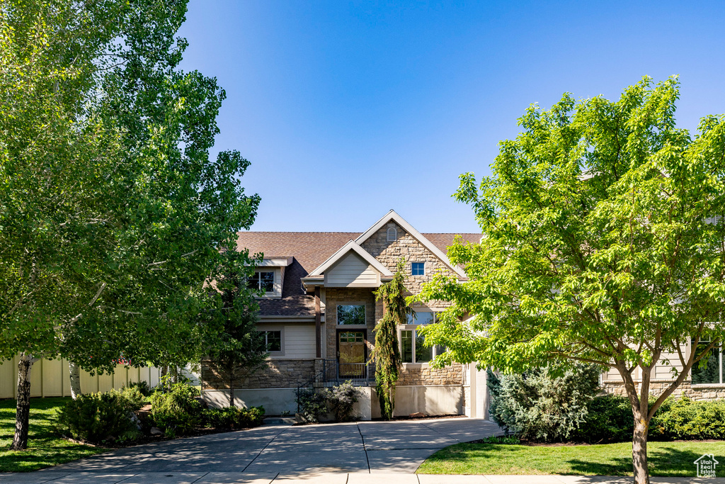 View of front of house featuring stone siding and concrete driveway