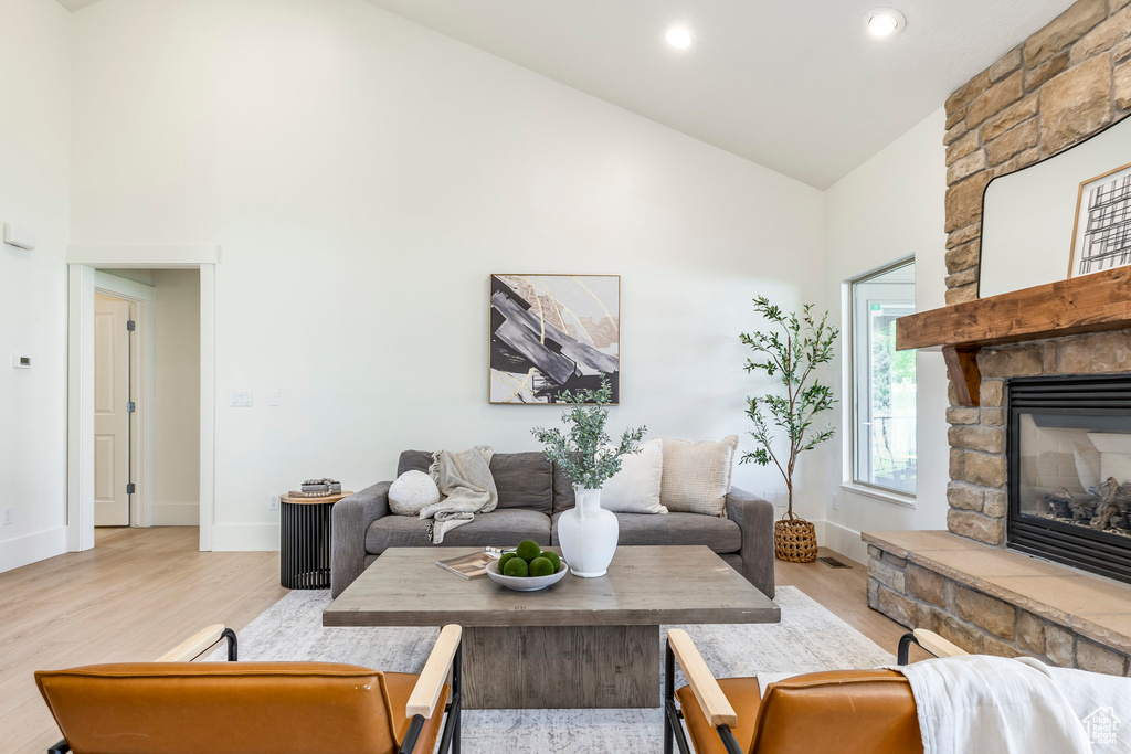 Living area featuring high vaulted ceiling, light wood-type flooring, a fireplace, baseboards, and recessed lighting