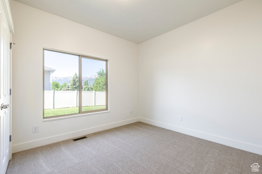Unfurnished room featuring light carpet, healthy amount of natural light, and baseboards