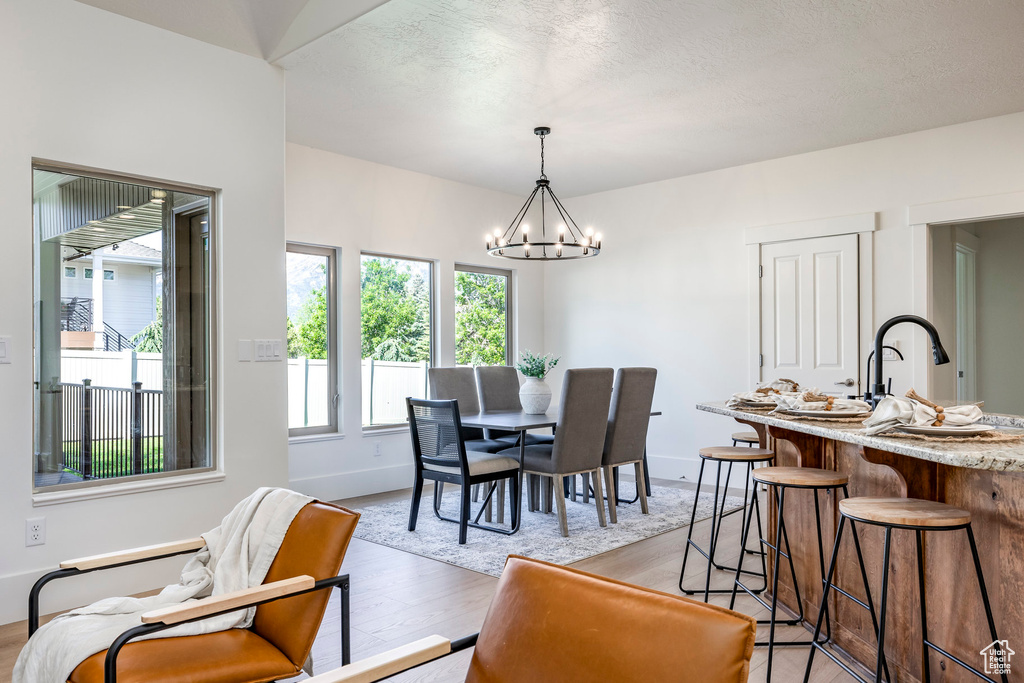 Dining space with a chandelier, light wood-style flooring, and baseboards