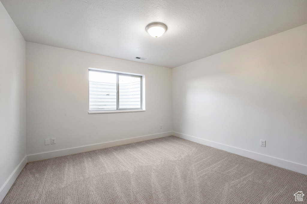 Spare room featuring light colored carpet and baseboards